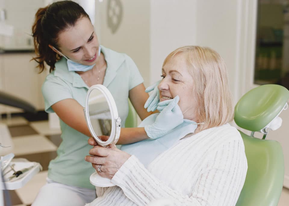 idosa se consultando com dentista após implante dentário